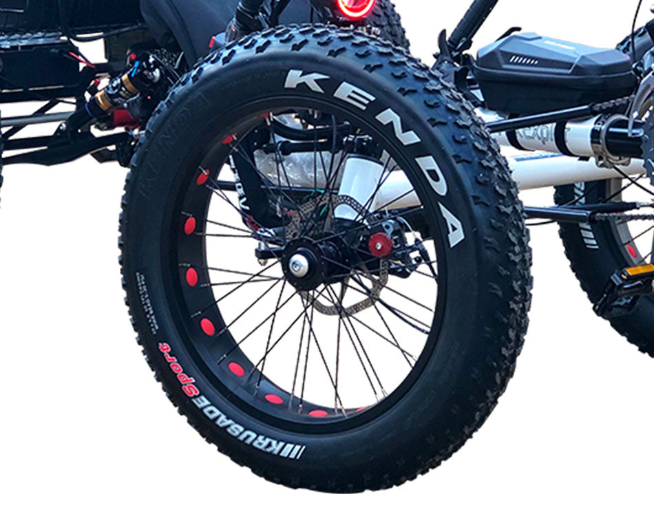 Close up of black off-road quadricycle tire with deep treading and Kenda branding on the tire wall