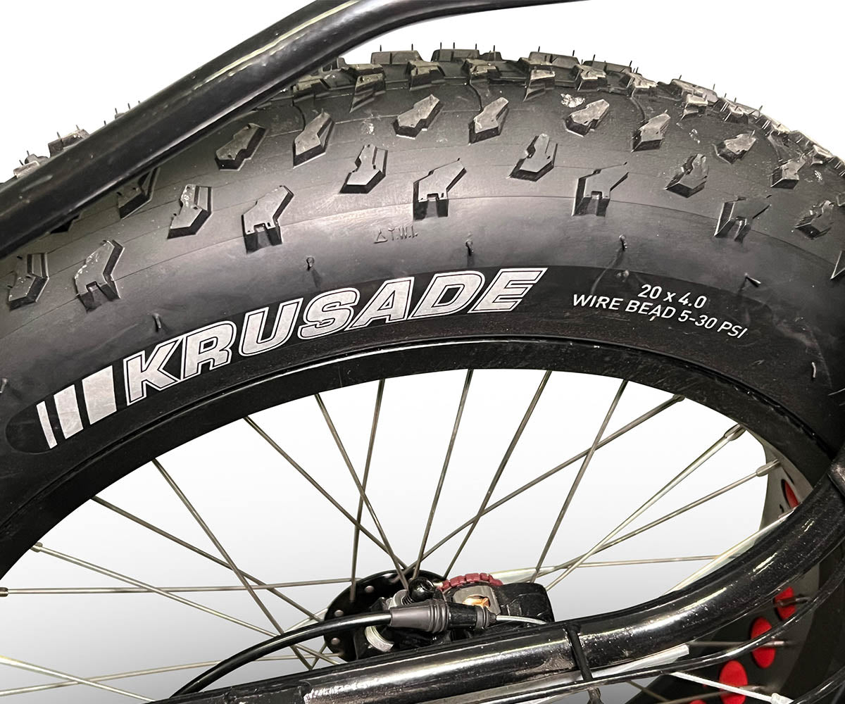 Close-up of a TrikExplor F420E tire with 'Krusade' branding and specifications showing 20 x 4.0, wire bead, 5-30 PSI.