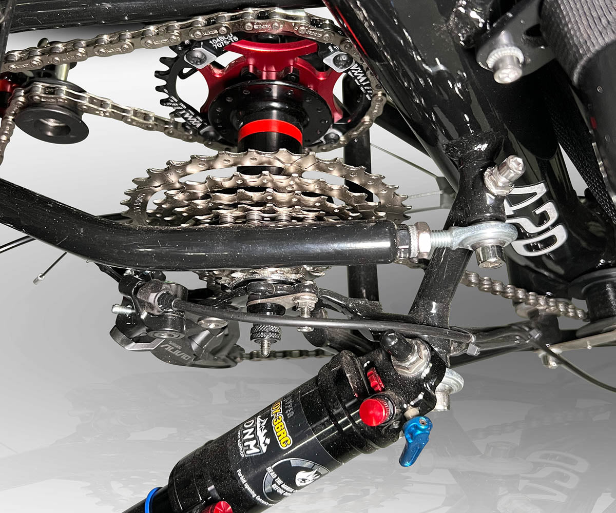 Close-up of the TrikExplor F420E's gear system and suspension, showing chain, sprockets, and shock absorber.