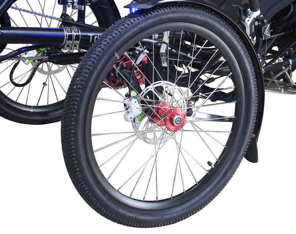 Close up of an all terrain trike tire with disk brakes, red metal hub, and white painted brake caliper 